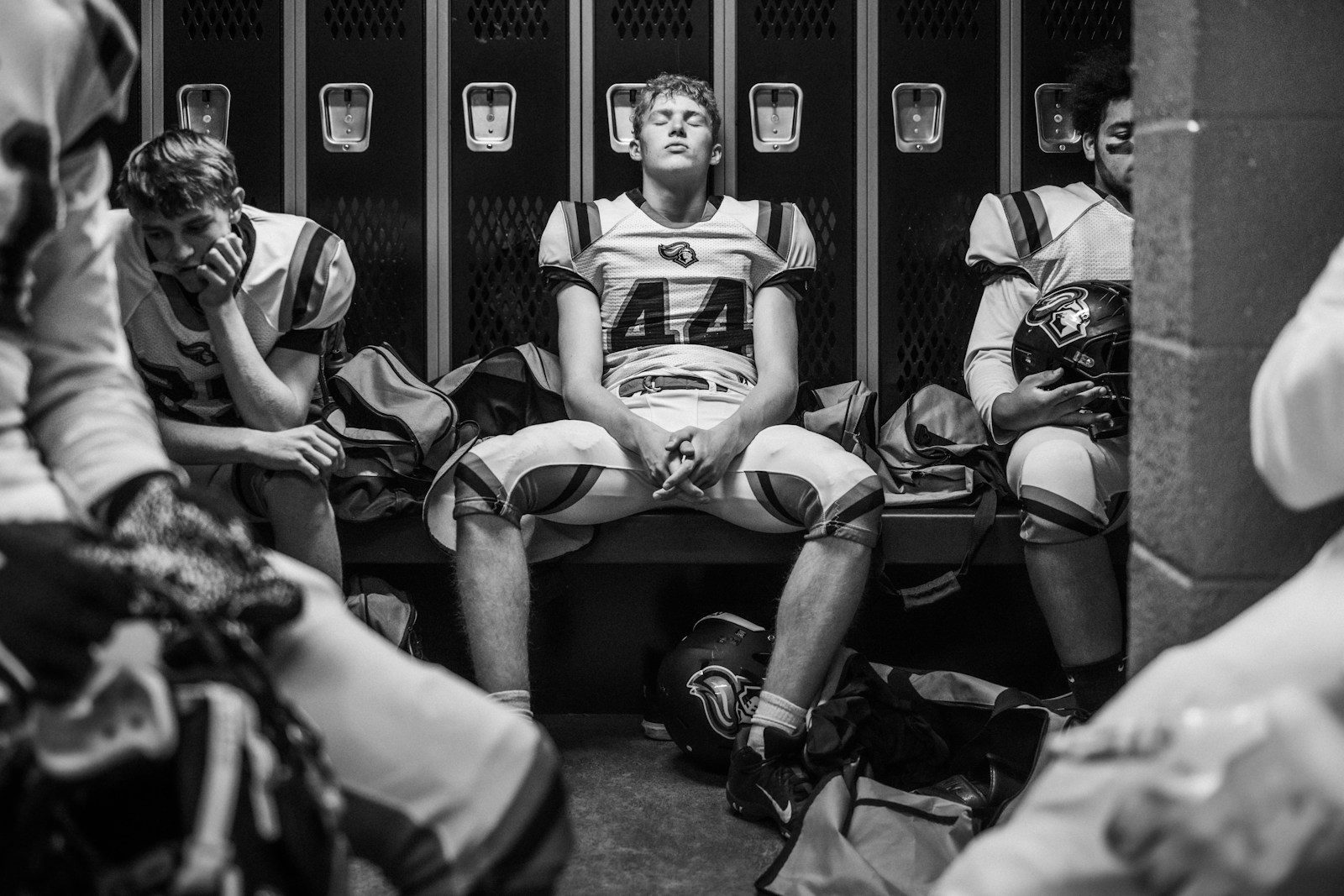 Photo by Tim Mossholder Football players sitting in a locker room.