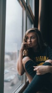 a woman sitting on a window sill looking out the window